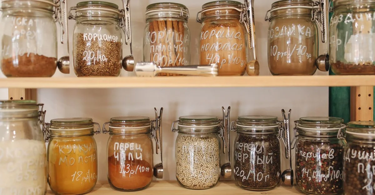 Garde-manger organisé avec des bocaux en verre contenant une variété d'épices et d'ingrédients sur des étagères en bois.