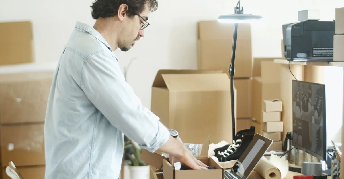 Homme d'affaires emballant des produits dans un bureau à domicile pour le démarrage d'une boutique en ligne.