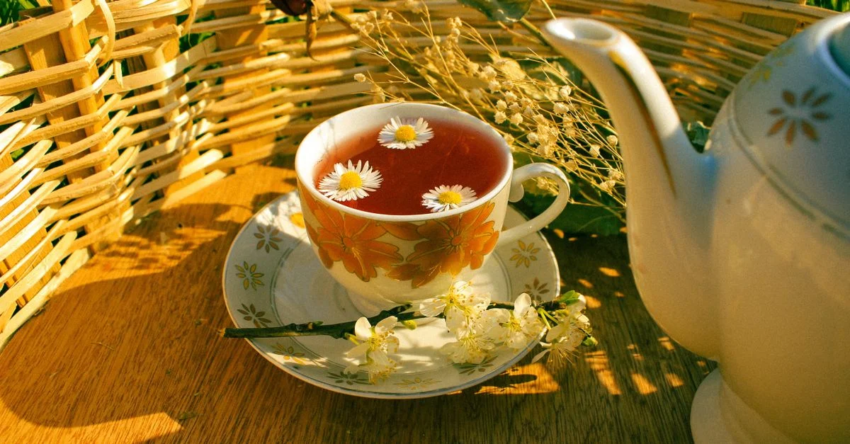 Un cadre serein avec du thé aux herbes infusé à la camomille, posé à côté d'une théière, en extérieur.