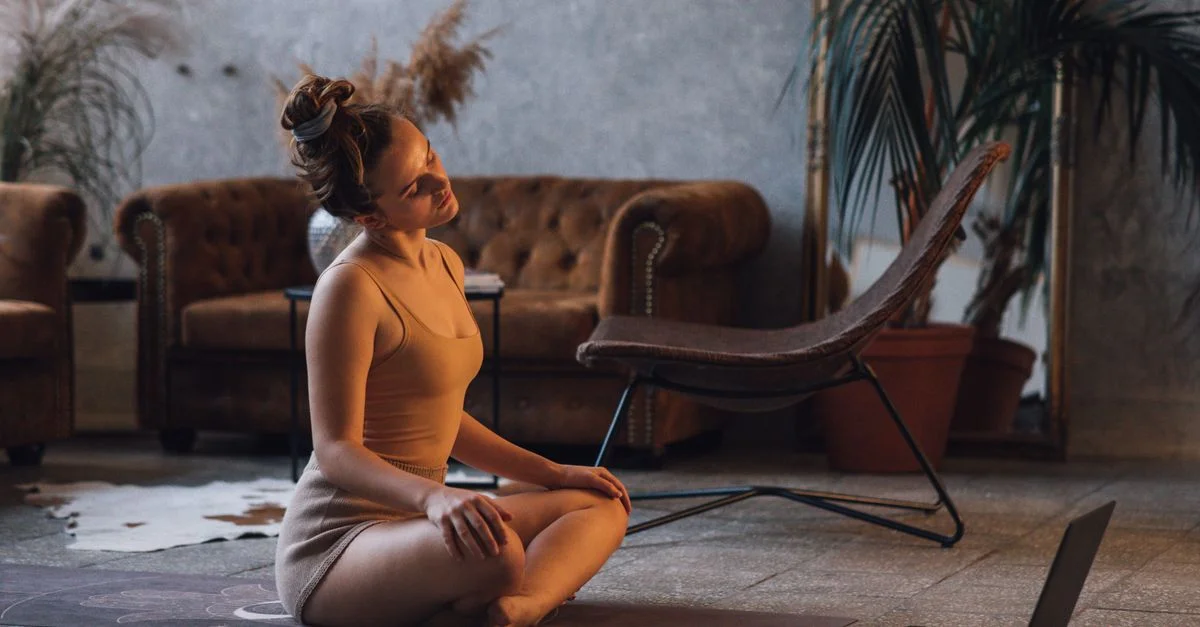Une femme faisant du yoga à l'intérieur, créant une atmosphère sereine et concentrée pour l'entraînement à domicile et la relaxation.