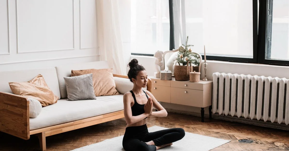 Une femme en vêtements de sport médite paisiblement à l'intérieur, favorisant le bien-être et la relaxation.