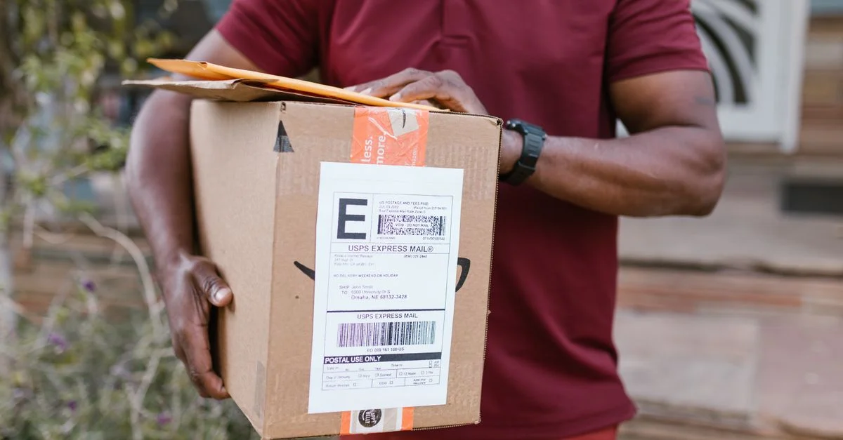 Gros plan sur un coursier livrant un colis avec une étiquette de service express USPS à l'extérieur.