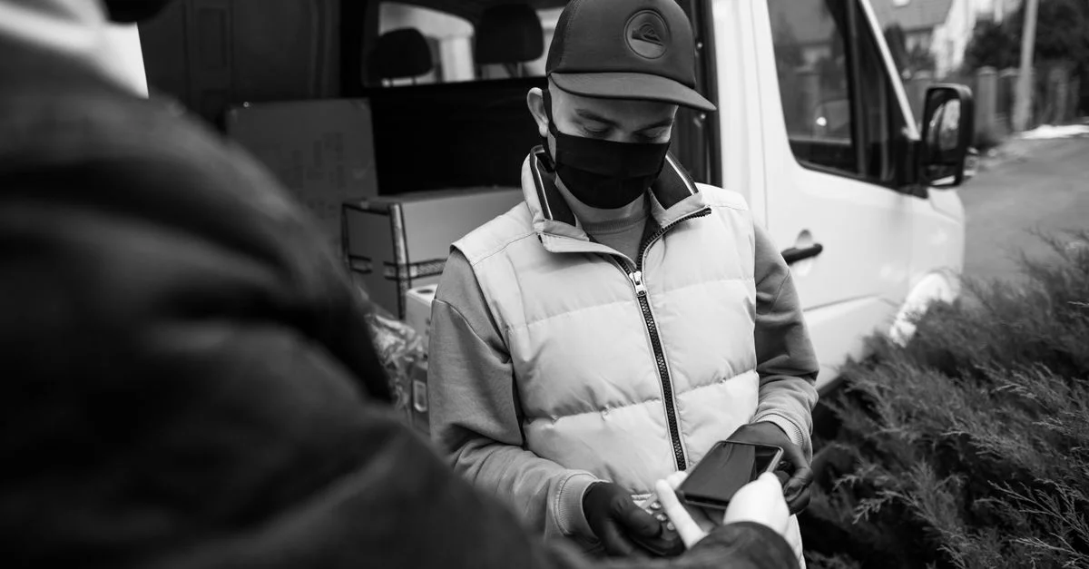 Livreur masqué accepte un paiement sans contact à l'extérieur. Concept de livraison sécurisée.